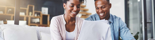stock photo young black couple sitting on couch living room laughing looking at sheaf papers
