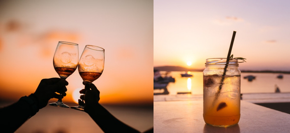 hands holding glasses toasting each other at sunset on beach drink in Mason jar on table with harbor at sunset in background